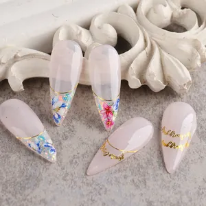Detailed view of rose gold long pointed press-on nails with floral patterns and gold lines