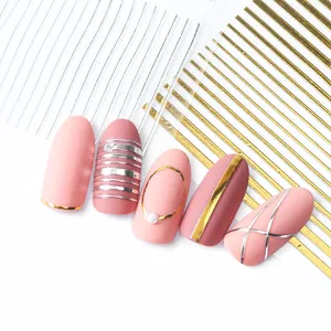 Detail of rose gold and silver 3D nail stripping tape on matte pink manicure with pearls