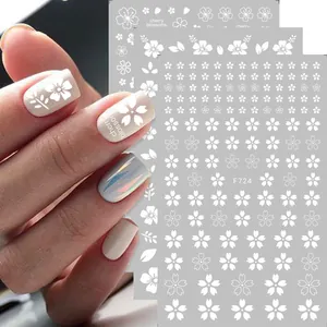 Macro detail of cherry blossom nail art stickers with white floral patterns on nails
