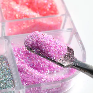 Macro shot of sugar nail powder in a 6-grid box with a metal tool scooping purple glitter