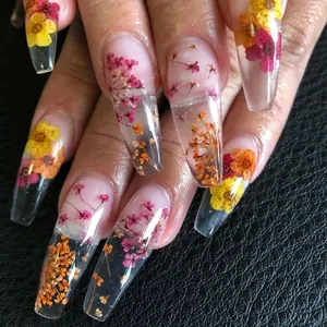 Dettaglio di unghie lunghe a bara con petali di fiori secchi colorati incorporati nell'acrilico
