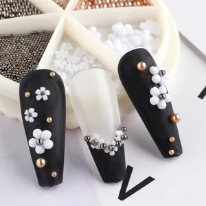 Detailed close-up of 3D white resin flowers and metallic beads on elegant nail art design