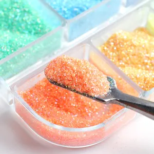 Close-up of vibrant mixed nail glitter sugar powder in a box with a metal scoop