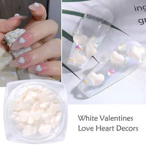 Dettaglio di ciondoli per unghie a cuore bianco e decorazioni in resina opaca in scatola