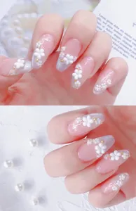 Detail of almond nails with 3D white flowers, silver glitter, and gold micro beads