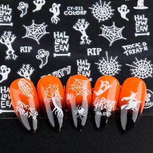 Macro view of white Halloween nail stickers with ghosts and pumpkins on orange gradient nails