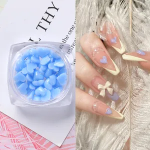 Charm per unghie a cuore blu chiaro in scatola con esempi di manicure eleganti