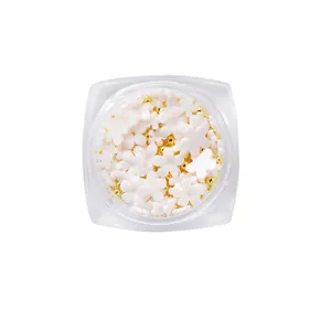 Mix of UV color-changing resin flower nail charms and gold beads in a clear bottle