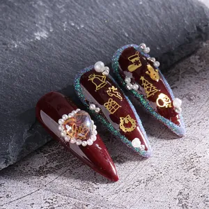 Faux ongles stiletto bordeaux de Noël avec flocons dorés et accents de perles