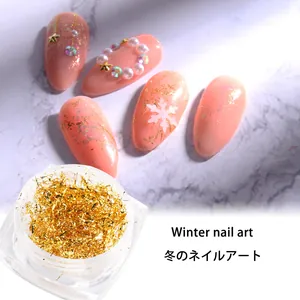 Detalle de láminas de oro para decoración de uñas de invierno con copos de nieve y perlas