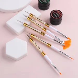 Dettaglio dei pennelli per nail art a doppia punta con strumenti per puntini e setole arancioni