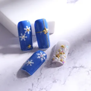 Detalle macro de nail art navideño con copos azules y diseños de árboles de perlas