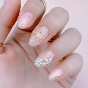 Primer plano de uñas rosa gelatina con copos de nieve, perlas y dijes metálicos de estrellas