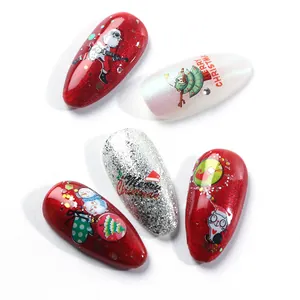 Detail of Christmas nail art tips with glitter, Santa and tree designs on white background