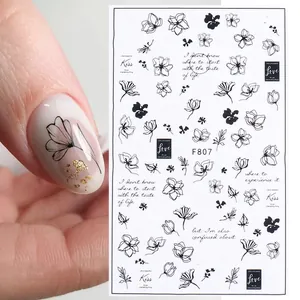 Detail view of F807 black floral nail stickers with artistic lettering on a model's hand