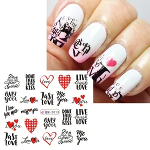 Macro view of nail water decals featuring red hearts and black romantic text for Valentine's Day