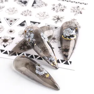 Close-up of floral nail stickers with black ink patterns and gold foil on almond nails