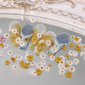 Detailed view of daisy nail charms with marble texture, pearls, and floral lace coating