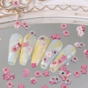 Macro shot of long trapezoid nails with yellow blue marble pattern and 3D floral petals
