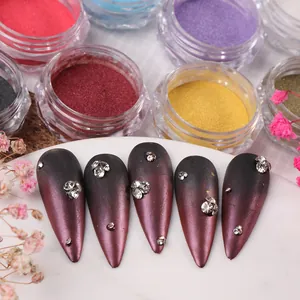 Macro view of gradient nail chrome powder jars and stiletto nails with white rhinestones