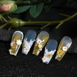 Detailed view of handmade blue and yellow gradient press-on nails with daisy and pearl accents