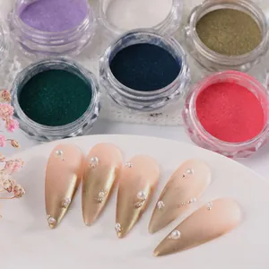 Close-up of macaron chrome nail powder jars with pearl and metallic bead nail art accents