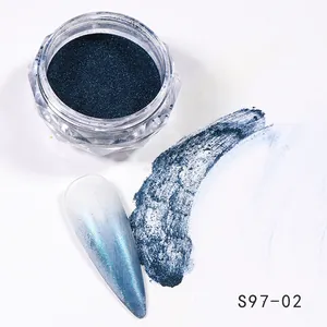 Detail view of dark teal chrome nail powder with blue-white gradient effect and applicator brush