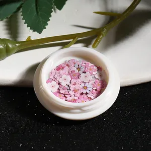 Macro detail of pink cherry blossom nail art sequins in a round white container