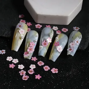 Detail of 3D pink cherry blossom nail charms with white pearls on blue marble press-ons