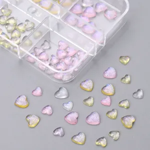 Aurora heart nail charms in pink and translucent colors inside a plastic storage grid box