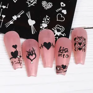 Detail of pink matte press-on nails with black heart patterns and nail stamping plate