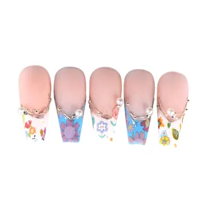 Détail de faux ongles fleuris avec perles 3D et motifs de tournesols dégradés
