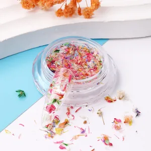 Close-up of colorful dried nail art flowers in a jar with application on clear nail tip