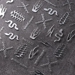 Detalle de pegatinas 3D para uñas en plata metálica con patrones de llamas y serpientes
