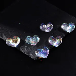 Iridescent aurora heart-shaped nail charms on a black slate surface for DIY manicures