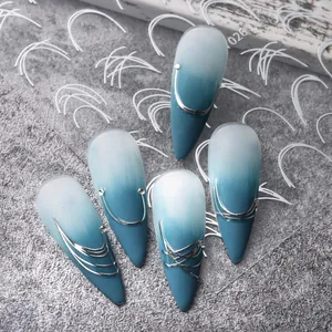 Vue détaillée d'ongles stiletto dégradés bleu et blanc avec lignes argentées et strass