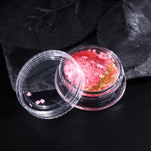 Vista macro di paillettes a fiori di ciliegio rosa e filo metallico dorato per nail art