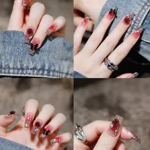 Red gradient press-on nails with 3D roses and butterflies, plus a silver ring set