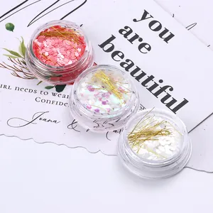 Dettaglio di paillettes a cuore e fili metallici dorati per nail art in barattoli