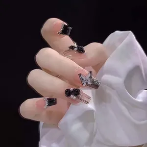 Detail of 3D matte black rose and butterfly charms on pink and black press-on nails