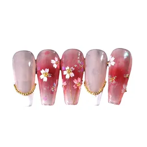 Unghie finte sfumate rosa con fiori di ciliegio 3D e accenti di catene metalliche