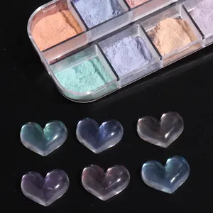 Makroaufnahme von irisierendem Aurora-Nagelpuder und 3D-Harzherzen auf schwarzem Hintergrund