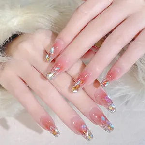 Primer plano de uñas postizas largas con degradado rosa y pedrería de cristal aurora