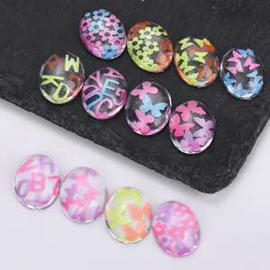 Close-up of clear resin nail charms with colorful letters, flowers and butterfly patterns
