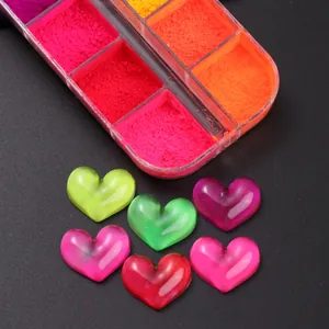 Makroaufnahme von Neon-Nagelkunst-Herzanhängern und fluoreszierendem Glitzerpuder-Set