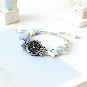 Minimalist quartz bracelet watch with blue star charm and woven strap on a soft background