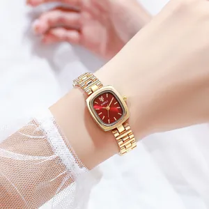 Détail d'une montre chaîne dorée élégante pour femme avec un cadran rouge soleil épuré