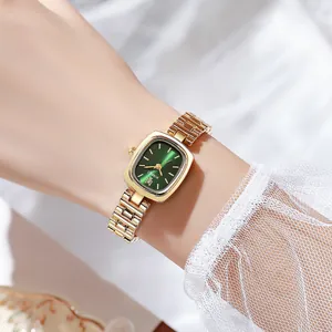 Détail de la montre élégante à chaîne dorée pour femme avec cadran vert foncé