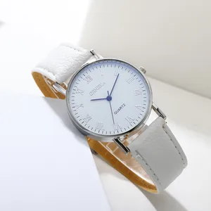 Macro shot of silver roman numeral watch dial with blue hands and white leather strap