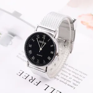 Montre à quartz minimaliste avec bracelet en maille argentée et cadran noir sur un magazine